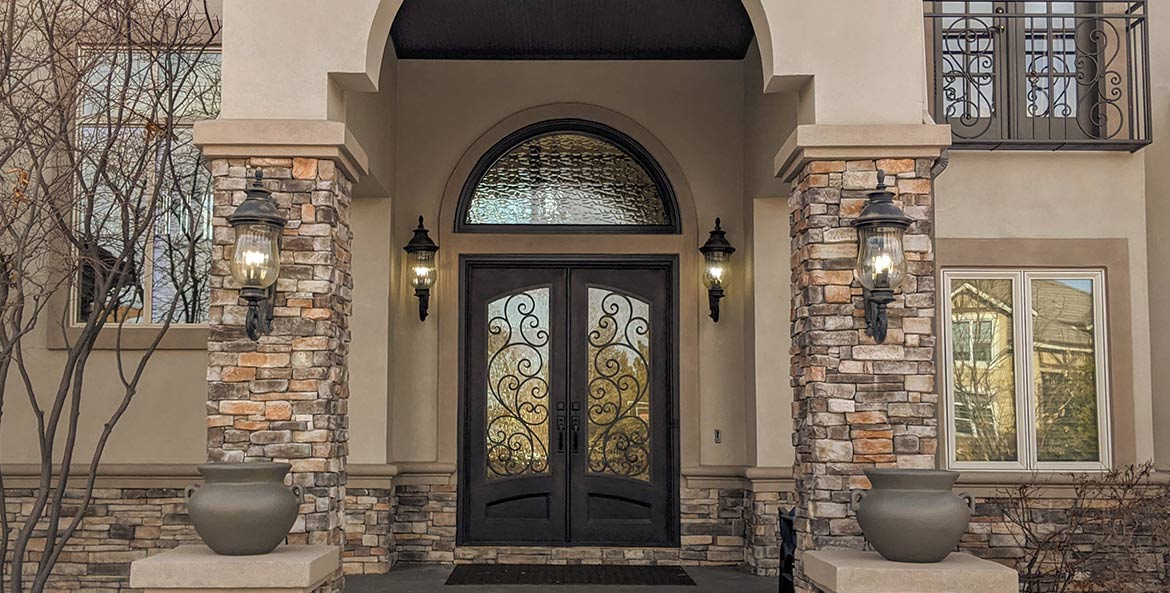 Site photo of Italian style double door iron entry, large round top transom, Flemish glass, Patented Thermal Break, Hand Rubbed Bronze finish.