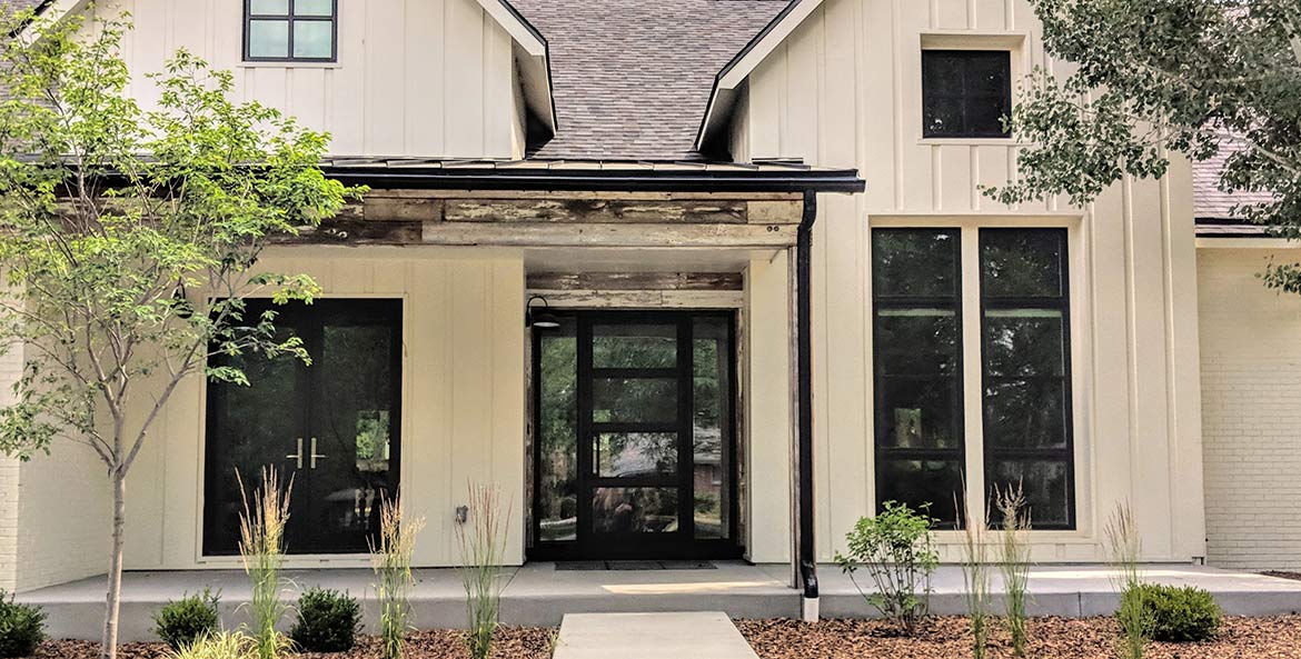 Site photo of modern farm house style with custom 4 panel clear glass contemporary iron entry, single panel sidelights, black finish, Patented Thermal Break