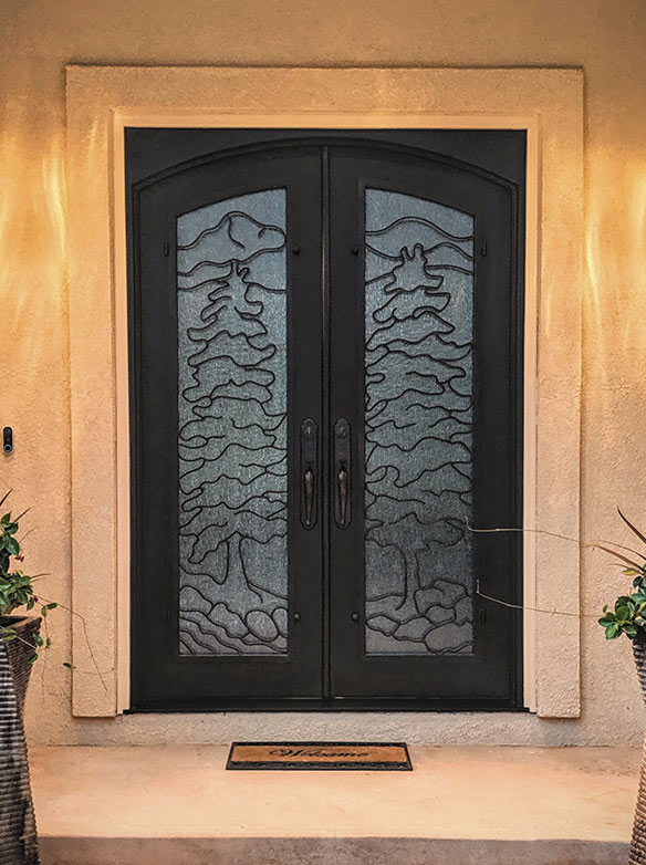Custom double door iron entry with single full lites, mountain scene with 2 single pine trees and brook in the forefront, Cotswald glass, Patented Thermal Break, Hand Rubbed Bronze finish