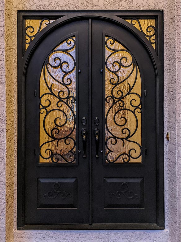 Custom design iron entry double round-top doors with square frame, glass corners with scrollwork, Flemish glass, Patented Thermal Break, Hand Rubbed Bronze finish