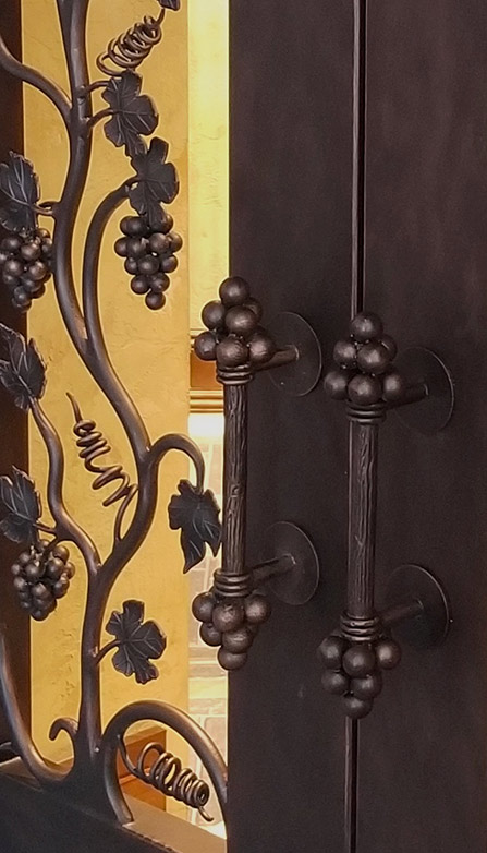 Detail of custom iron door pulls with iron grapes shown in adjacent picture